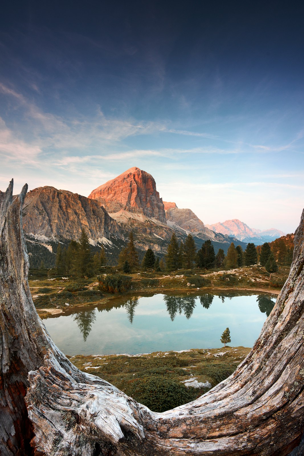 A calm alpine lake reflecting a rocky peak at golden hour