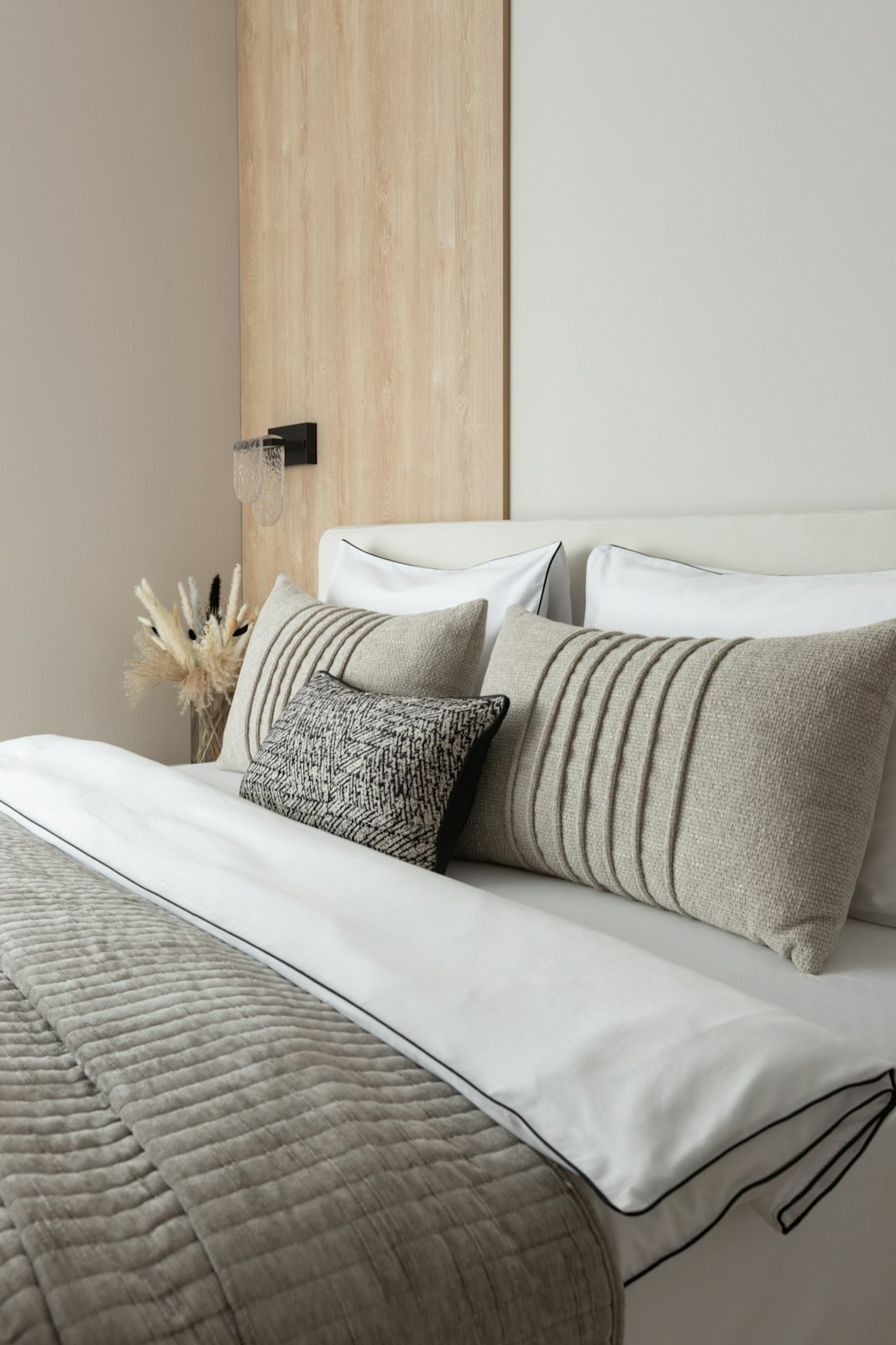 A made bed with striped linen pillows against an oak headboard