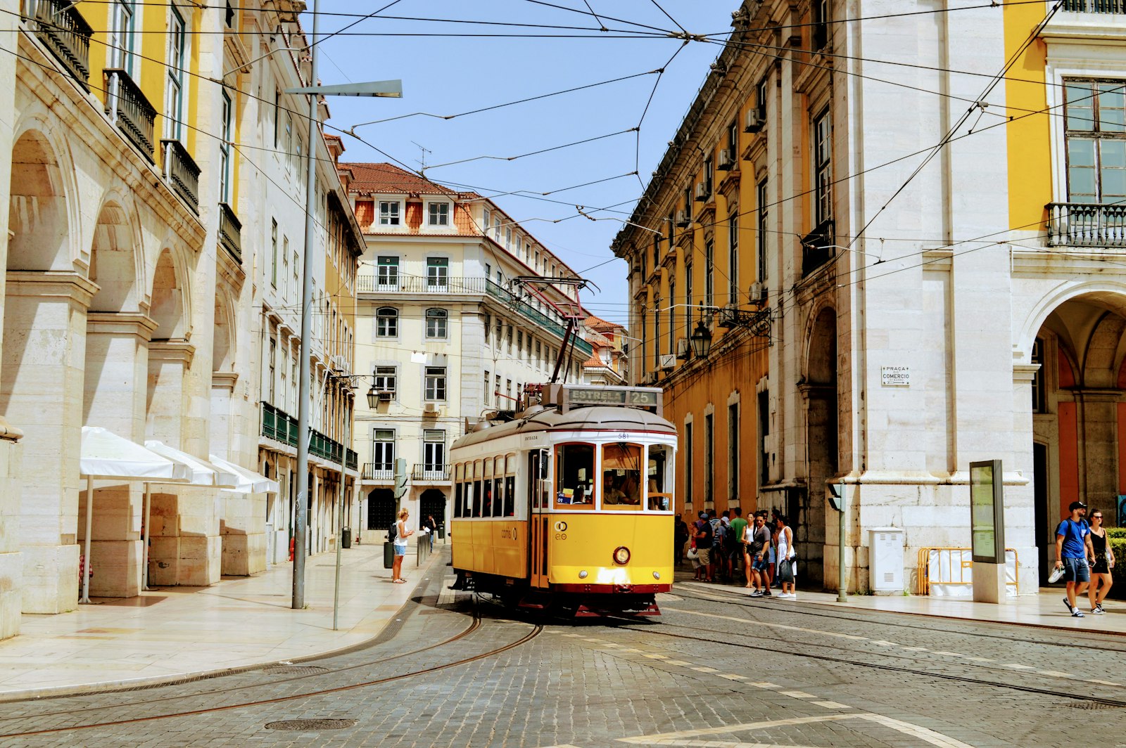 A yellow tram on a street lined with historic buildings in Lisbon