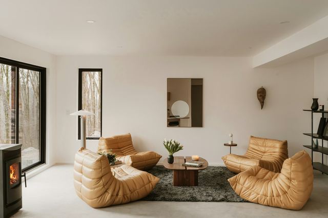 A living room with tan leather chairs around a low fireplace