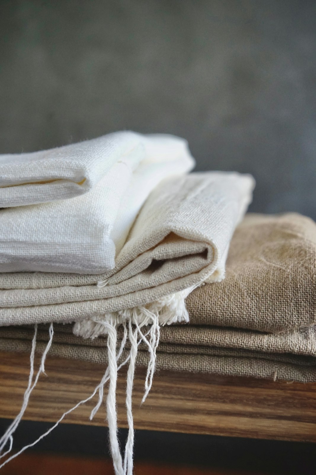 Folded natural linen throws with fringed edges in soft window light