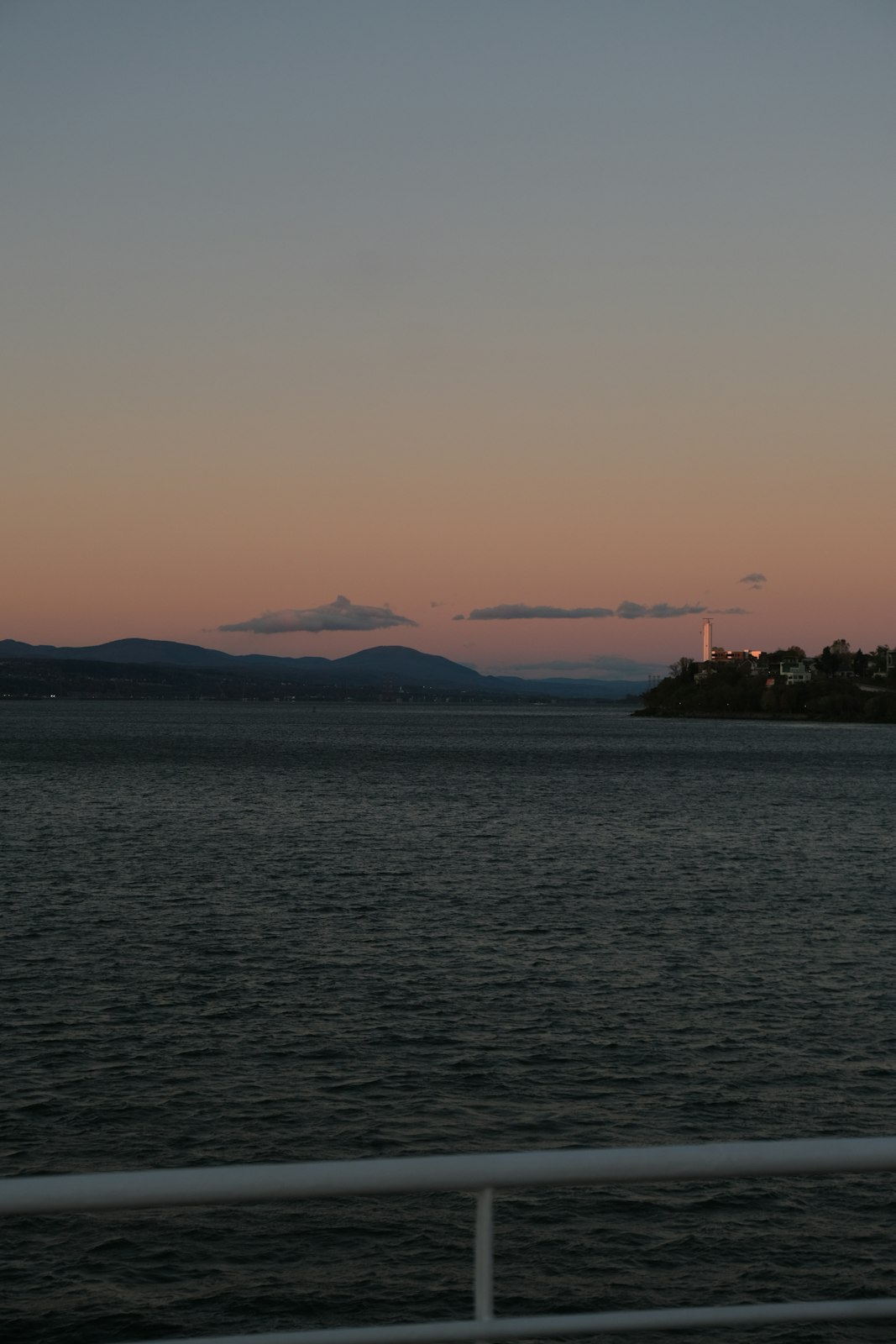 A calm sea at dusk with a low island on the horizon
