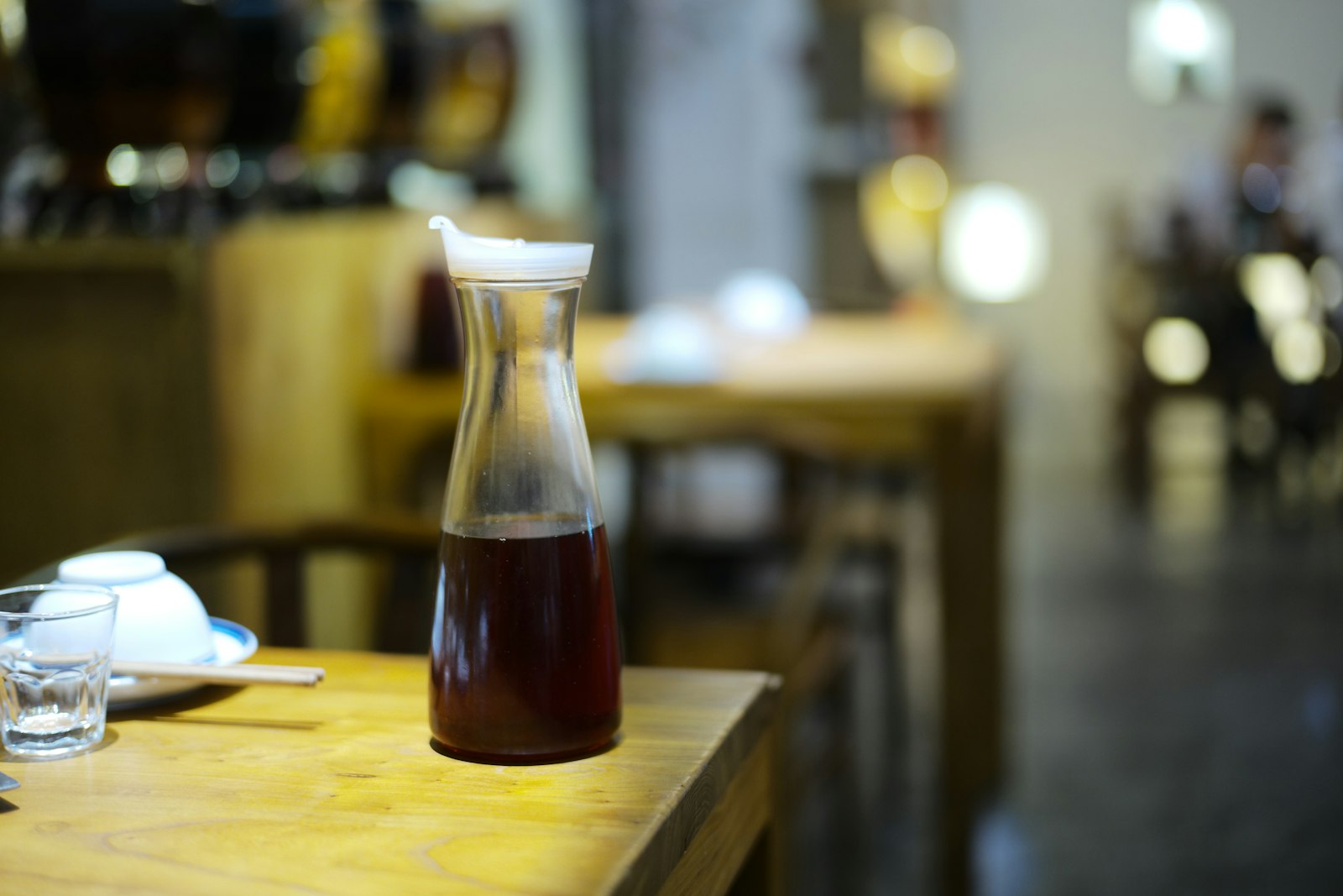 A glass carafe of red wine on a bar table in low evening light